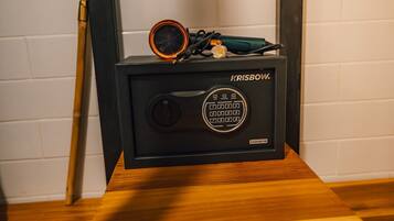 A black speaker with a circular grill and a control panel on a wooden surface against a white tiled wall.