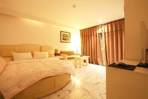 Habitación de hotel con cama, escritorio, silla, lámpara y ventana con cortinas.