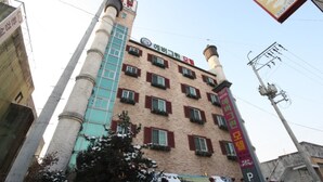Un edificio de varios pisos con una torre destacada, varias ventanas y un letrero que indica un hotel.