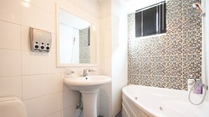 Un baño con lavamanos blanco, espejo, inodoro y bañera con mosaicos.