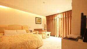 Una habitación de hotel con una cama, un escritorio, una silla, una mesita y una ventana con cortinas.