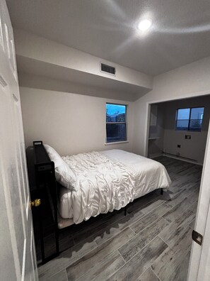 Ein Schlafzimmer mit Bett, Fenster, Tür und Blick nach draußen.