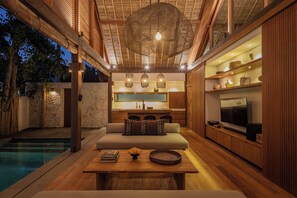 A modern interior with a pool, wooden furniture, and a kitchen area. - Villa Kokomo - 2 Bedroom Villa (Nusa Lembongan)