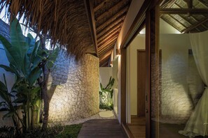 A stone pathway leading to a room with a thatched roof and a glass door. - Villa Kokomo - 2 Bedroom Villa (Nusa Lembongan)