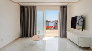 Una habitación moderna con puerta de vidrio corredera que da a un patio, un televisor de pantalla plana en la pared y una pequeña mesa con una silla.