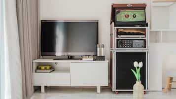 Una sala de estar moderna con una televisión de pantalla plana, un sistema de sonido y una mesita con un libro y un objeto amarillo.
