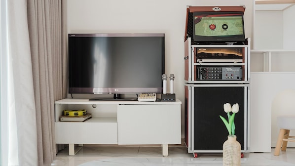 Una sala de estar moderna con una televisión de pantalla plana, un sistema de sonido y una mesita con un libro y un objeto amarillo.