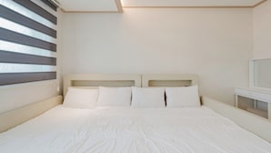 Un dormitorio con cama, almohadas, mesita de noche y espejo.