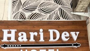 Un letrero de madera con la leyenda 'Hari Dev HOTEL'.