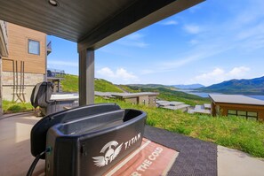 Un espace extérieur abrité, aménagé avec des sièges, et offrant une vue sur un lac et des collines.