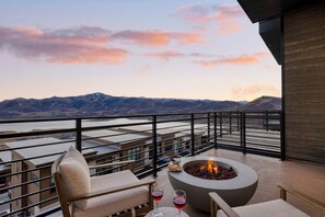 Ein Balkon mit Feuerstelle, Sitzgelegenheiten und Blick auf Berge.