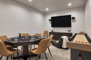 Een kamer met een pooltafel, een blackjack tafel en een aan de muur bevestigde televisie.