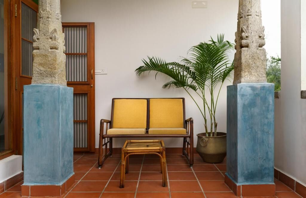 Une pièce avec un canapé, une petite table, une plante en pot et des piliers en pierre.