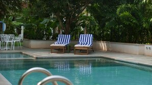 A swimming pool with lounge chairs and a white fence.
