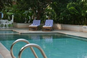 A swimming pool with lounge chairs and a white fence.