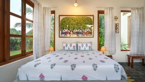 A bedroom with a large bed, a painting above the bed, and a view of the outdoors through the window.