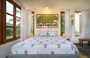 A bedroom with a large bed, a painting above the bed, and a view of the outdoors through the window.