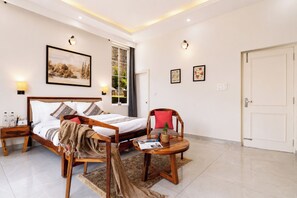 A modern hotel room with a wooden bed, a round wooden table, a nightstand, a large window with a view, and a door. - Alaya Stays Gable Pine with Pool (Kasauli)