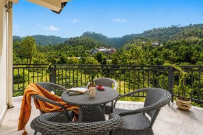 A balcony with wicker furniture, a book, a mug, and a toy car. - Alaya Stays Gable Pine with Pool (Kasauli)