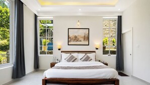 A bedroom with a large bed, two bedside tables, a painting on the wall, and a view through the window. - Alaya Stays Gable Pine with Pool (Kasauli)