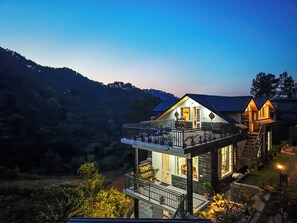 A two-story house with a balcony, a staircase, and a view of the surrounding forest. - Alaya Stays Gable Pine with Pool (Kasauli)