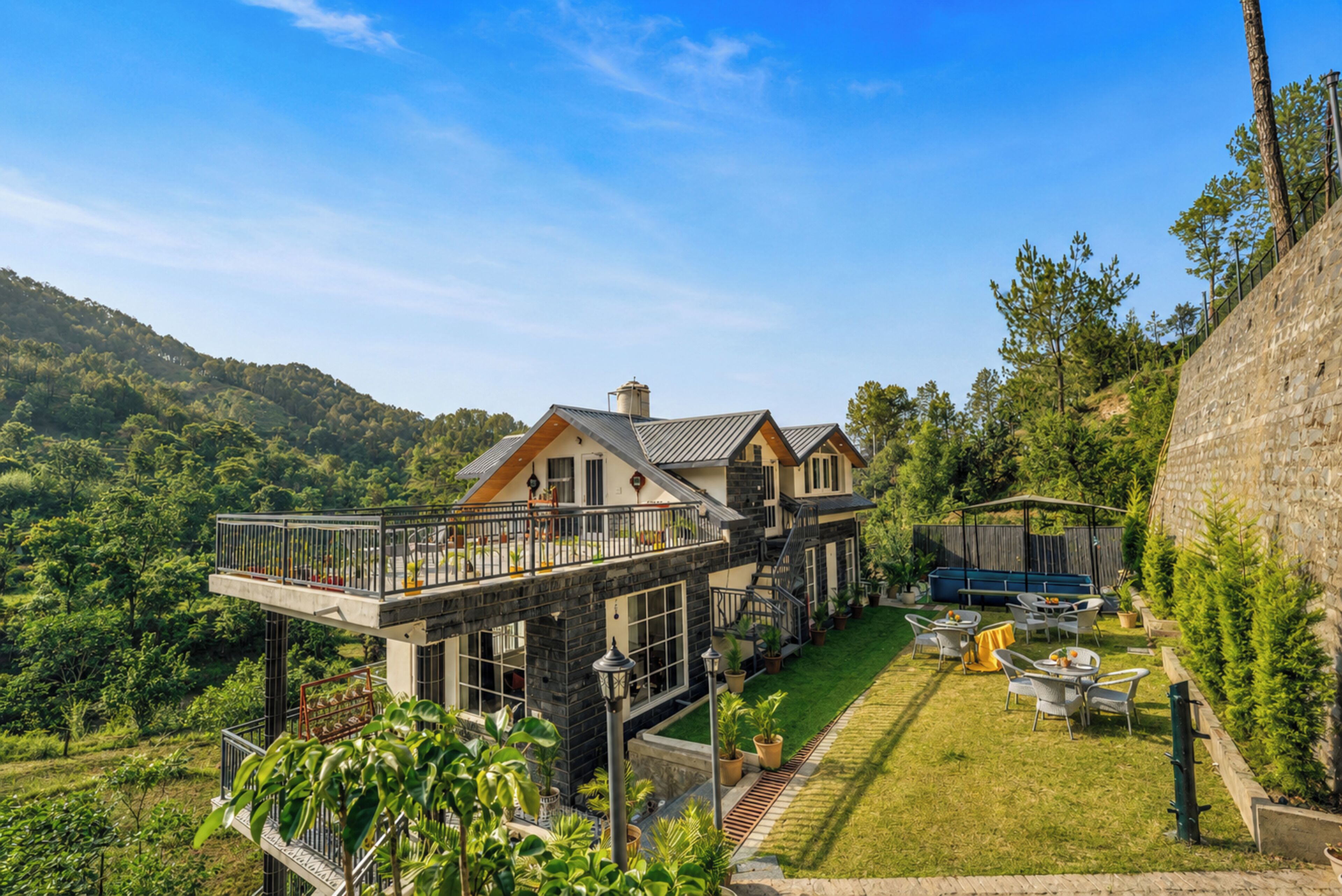 A large house with a balcony, a lawn, and a stone wall.