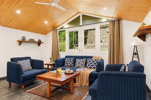 Una habitación con techo de madera, un conjunto de sofás, una mesita de centro, una lámpara y vistas a través de una ventana.