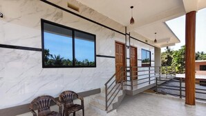 A modern interior with marble walls, a staircase, and two wooden chairs. - Anthik Family Homestey (Bhatkal)