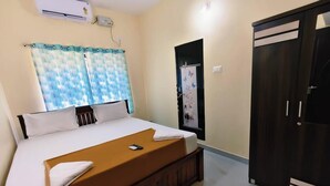 A bedroom with a bed, a wardrobe, and an air conditioning unit. - Anthik Family Homestey (Bhatkal)