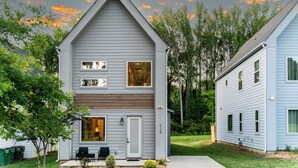 Une maison à deux étages avec un porche à l’avant, un garage et une pelouse bien entretenue.