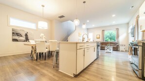 Une cuisine moderne avec un îlot central, un coin repas avec des chaises et un salon avec un canapé.