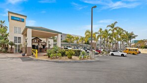 Un motel avec une enseigne, un parking couvert et des palmiers.