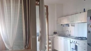 Una cocina con una mesa de comedor, sillas y vistas a la habitación contigua.