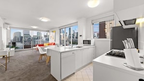 Una cocina moderna con armarios blancos, horno empotrado y un amplio ventanal con vista a la ciudad.