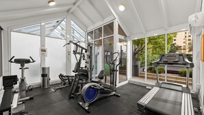 Un gimnasio con diverso equipo de ejercicio, incluyendo cintas de correr, elípticas y máquinas de pesas.