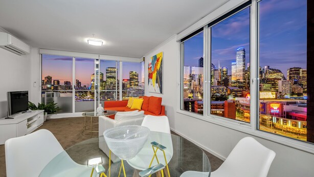 Una sala de estar moderna con vista a la ciudad, amplias ventanas y muebles contemporáneos.