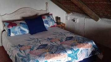 Une chambre à coucher avec un lit, une table de chevet, une lampe et un plafond en pente.
