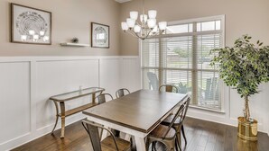 Un coin repas avec une table en bois, des chaises, un lustre et une plante en pot.