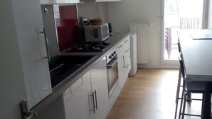 Eine moderne Küche mit weißen Schränken, einem roten Gerät, einer Mikrowelle und einem Herd.