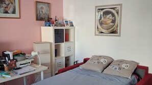 Ein Schlafzimmer mit Bett, Schreibtisch und Regalelement.