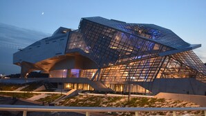 Ein modernes architektonisches Gebäude mit einem einzigartigen, kantigen Design, eine große Glasfassade und einen markanten Eingangsbereich.