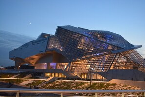 A modern architectural building with a unique angular design, featuring a large glass facade and a prominent entrance area. - FESTIVAL OF LIGHTS (Lyon)