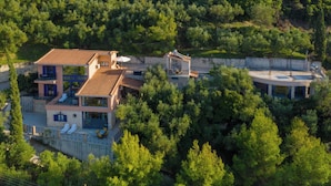 Una casa a due piani con una terrazza, immersa nel verde.