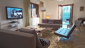 A living room with a sofa, a coffee table, a TV, and a view of the outside.