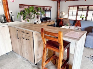 A kitchen with wooden cabinets, a wooden chair, a potted plant, a television, and a table with a menu.