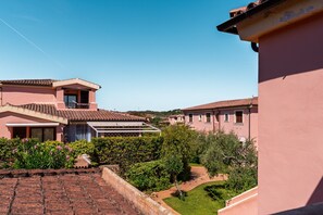 Ein Wohngebiet mit terrakottafarbenen Dächern, rosa gestrichenen Gebäuden und blauem Himmel.