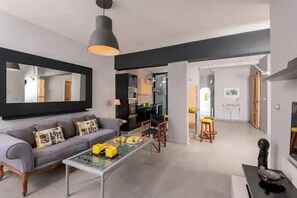 Un salon moderne avec un canapé, une table basse et un coin repas avec des chaises.