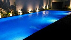 A swimming pool with a blue hue, surrounded by walls with light fixtures. - Sany Rosa Hotel (Bandung)