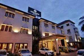 A hotel with a sign reading 'SANY ROYA HOTEL' and multiple cars parked in front.