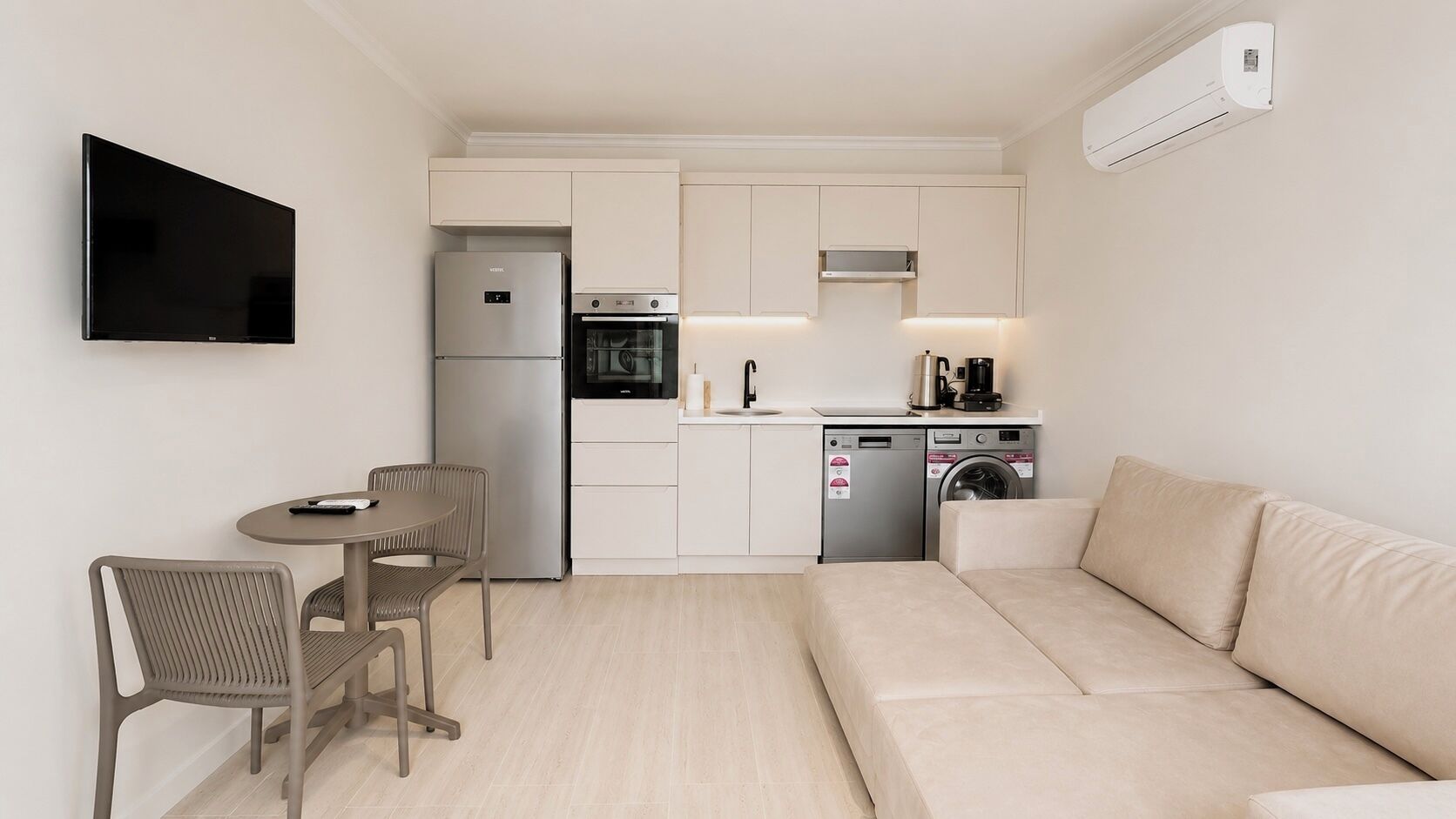 Een moderne keuken met een koelkast, oven, vaatwasser en koffiezetapparaat.